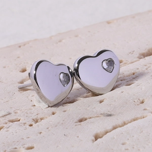 Macro shot of silver heart stud earrings with cubic zirconia on a stone surface