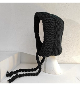 Détail du bonnet en grosse maille noire avec liens tressés et texture en laine