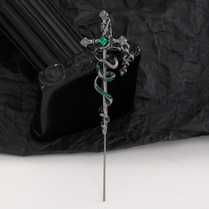 Macro detail of gothic sword hair pin with green gemstone and snake carving