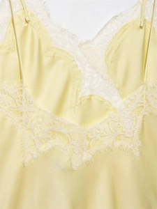 Detailed close-up of pale yellow satin top with intricate eyelash lace trim at the neckline