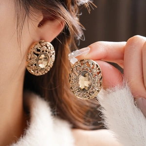 Macro detail of vintage gold hollow oval earrings featuring a champagne center stone