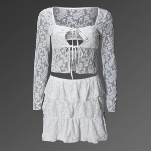 Detailed close-up of white lace texture on long sleeve tie-front top and tiered skirt