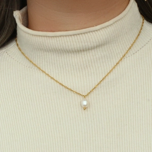 Dettaglio di una collana a catena dorata con un pendente di perla bianca lucida ed elegante