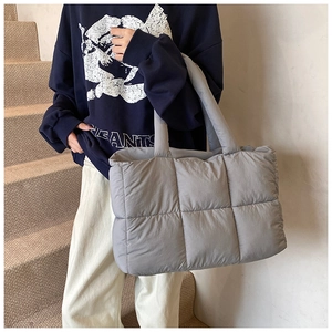 Detail of grey quilted down tote bag showing large square stitching and puffy nylon texture