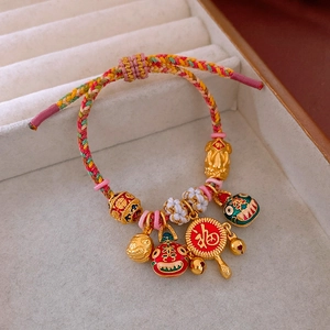 Détail du bracelet tissé avec pendentifs tigre dorés et breloque porte-bonheur Fu
