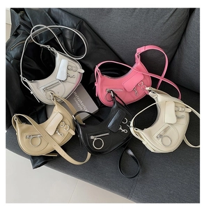 Collection de sacs bandoulière style punk en argent, rose, noir et crème sur sofa