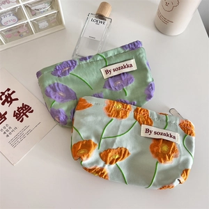 Close-up of floral embossed cotton pouches with zip closure and white brand labels