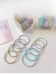Detail of multi-colored spiral elastic hair ties in a clear storage box on a white table