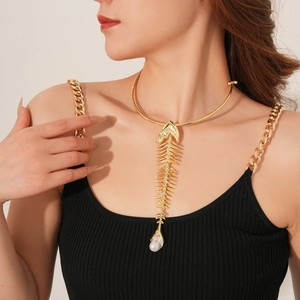 Close-up of a gold fishbone pendant necklace featuring a single pearl on a female model