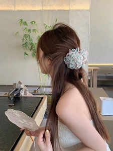 Dettaglio di un grande fermaglio per capelli floreale in tessuto indossato su capelli lunghi