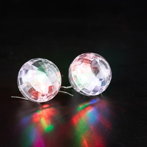 Macro shot of glowing LED disco ball earrings with vibrant red and green reflections