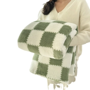 Green and white checkered sher white checkered sherpa fleece blanket held by model for softness display