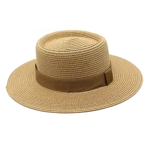 Detailed view of natural straw boater hat with a flat brim and brown grosgrain ribbon
