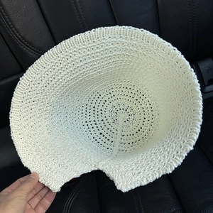 Foldable beige knit fisherman hat with openwork weave on a dark textured surface
