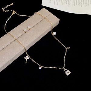 Detailed view of gold plated necklace with key, lock and pearl pendants in a gift box