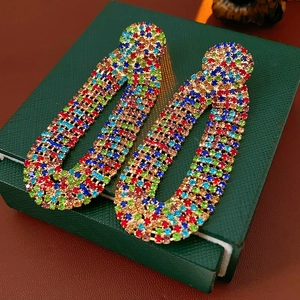 Detailed close-up of vintage hoop earrings with multicolored zircons on green jewelry box