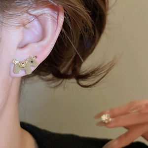 Close-up of a velvet flocked puppy earring worn on model ear in soft warm lighting