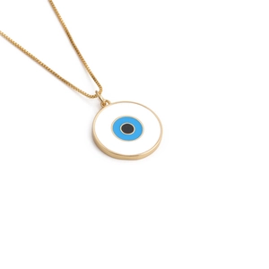 Detail of a gold box chain necklace featuring a blue evil eye pendant on white background
