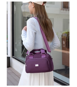 Outdoor shot of a waterproof purple nylon bag showing crossbody styling on a model