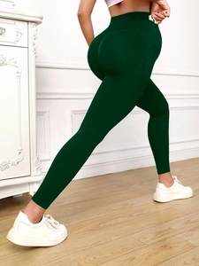 Detail view of dark green high-waisted yoga pants showing lifting effect and slim fit cut