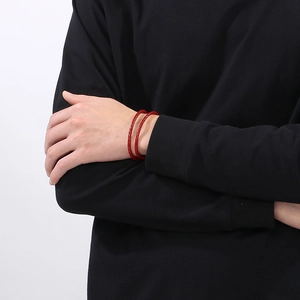 Primo piano di un bracciale in pelle intrecciata rosso acceso a doppio giro sul polso