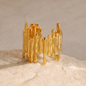 Detail of gold lava textured open ring displayed on natural stone with warm lighting