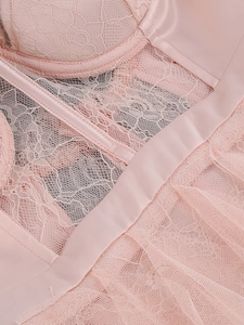 Detailed close-up of pink lace crochet and smooth satin fabric on a mesh dress