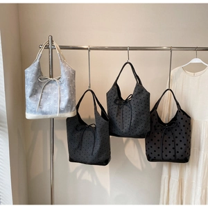 Detail view of four polka dot and striped bucket bags hanging on a display rack