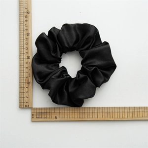 Detail view of large black satin scrunchie showing 12cm diameter on wooden ruler