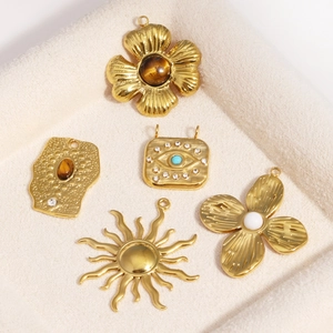 Five vintage gold plated titanium steel flower and sun pendants with opal in a beige tray