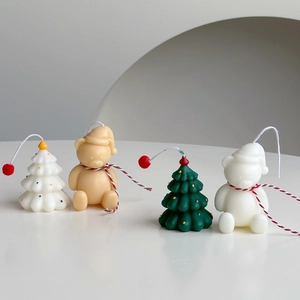 Close-up of mini Christmas tree and bear shaped scented candles with red ornaments