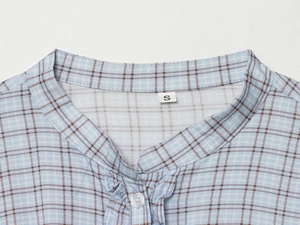 Close-up of light blue plaid shirt collar showing fine cotton texture and precise stitching