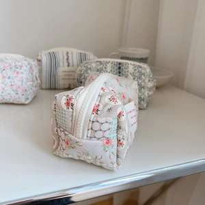 Detail of floral quilted cotton makeup bag featuring soft fabric and white zipper