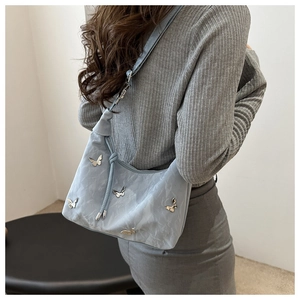 Detail of light blue nylon bag with silver butterfly ornaments and knotted shoulder strap