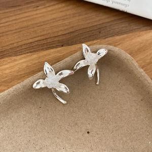 Nahaufnahme der silbernen Blumen-Ohrstecker mit weißer Perle auf einem Tablett