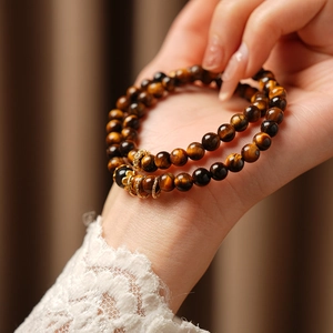Close-up of double-layered tiger eye bead bracelet with gold accents on model wrist