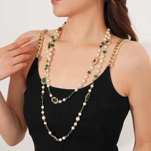 Detail of vintage layered pearl necklace with green gemstones and golden chains