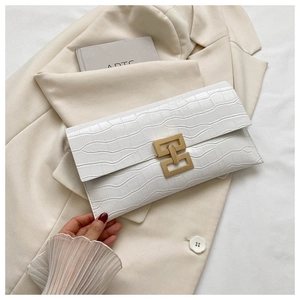 Detail of white crocodile-embossed envelope clutch bag with gold geometric metal clasp