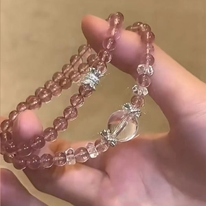 Macro view of strawberry crystal beaded bracelet with silver butterfly charm and clear bead