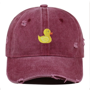 Detail of distressed embroidery featuring a yellow duck on a burgundy baseball cap