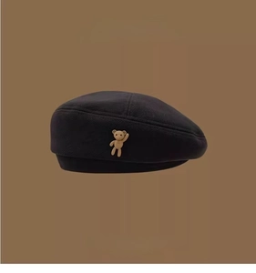Detail showing the woven texture of the beret with a cute beige bear ornament