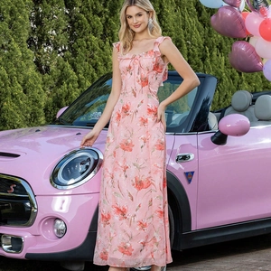 Détail d'une robe longue fleurie rose avec col à nouer devant une voiture ancienne