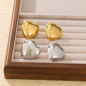 3D heart earrings in gold and silver finish displayed on a beige fabric tray