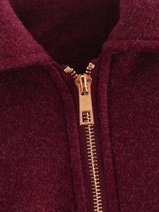 Nahaufnahme der weinroten Tweedjacke mit hochwertigem goldenem Metallreißverschluss
