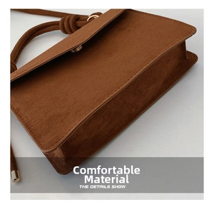Detailed view of the dark brown suede bag with precise stitching and golden metal snap buckle