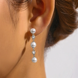 Detail of S925 silver tassel earrings with pearls and cubic zirconia on a female model