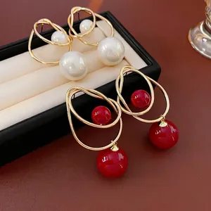 Elegant geometric drop earrings with pearls and red beads in gold-toned rings