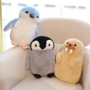 Soft plush penguin and walrus dolls displayed on a beige sofa with fluffy texture details