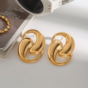Modern abstract fluid gold earrings with high-polish metallic finish on white sunglasses