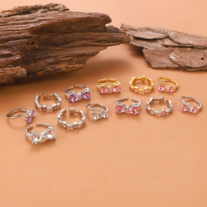 Detailansicht von Silber- und Goldringen mit Herz, Schmetterling und rosa Kristallen